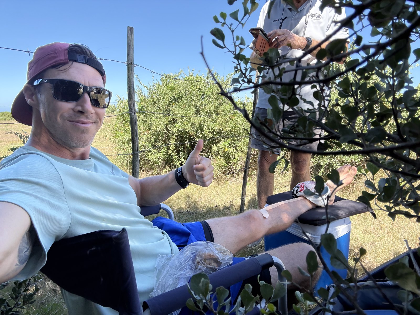 Justin King giving a thumbs up from a camp chair, leg up, during his 10 marathons in 10 days